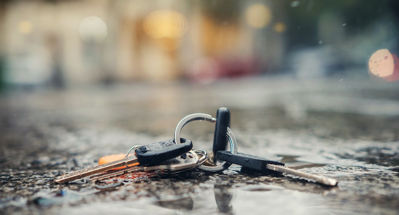 Set of lost keys on the ring on wet ground on the street, selective focus