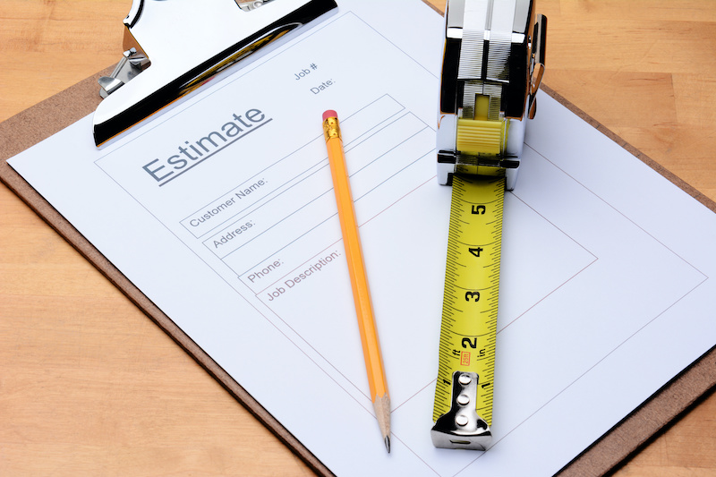 Closeup of a Contractors estimate form with a pencil and tape measure on a wooden table. Horizontal format filling the frame.